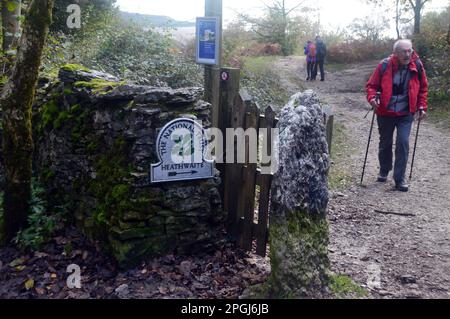 Old Mature man Walking vorbei am National Trust Wegweiser für Heathwaite Nature Reserve nahe Arnside Knott, Arnside, Cumbria, England, Großbritannien. Stockfoto