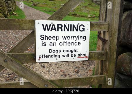 Warnschild am Wooden Gate (Dogs will be Shot) zum Farmers Field in Mickleden Valley, Lake District National Park, Cumbria, England, Großbritannien. Stockfoto