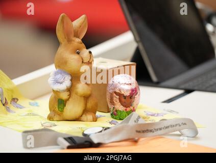 Potsdam, Deutschland. 23. März 2023. Ein Osterhasen aus Porzellan und ein Schokoladenei, bedruckt mit dem Bild eines Osterlamm-Stands auf dem Tisch des CDU-Stellvertreters Walter-Mundt während der staatsparlamentarsitzung. Kredit: Soeren Stache/dpa/Alamy Live News Stockfoto