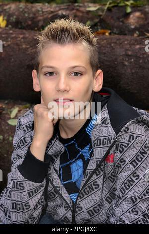 Teenager, der vor gefalzten Baumstämmen sitzt, Blick nach vorne Stockfoto