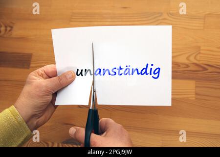 Ein Wort auf einem Papier, die Negation "un" ist abgeschnitten, unanstaendig - anstaendig, unanständig - anständig Stockfoto