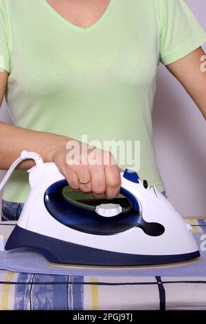 Frau bügelt Männerhemd, klassische Rollenverteilung Stockfoto