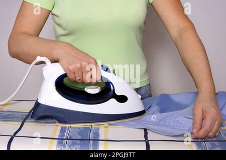 Frau bügelt Männerhemd, klassische Rollenverteilung Stockfoto