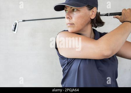 Golfer mit Cap hält ihren Iron Golf Club an einem sonnigen Tag in der Schweiz. Stockfoto