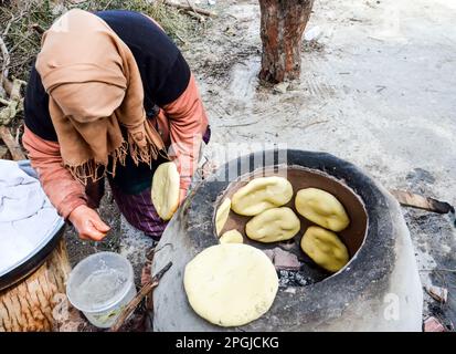 Tunis, Tunesien. 22. März 2023. Tunis, Tunesien, 22. März 2023. Eine tunesische Frau backt das Tabouna-Brot in einem traditionellen Tonofen, bevor sie es auf einem Markt in Tunis verkauft. Tabouna ist ein altes tunesisches Brot aus Weizen-, Grieß- oder Gerstenmehl, das an den Wänden eines traditionellen Terrakotta-Ofens gekocht wird. Tabouna ist besonders beliebt während des heiligen muslimischen Monats Ramadan (Kreditbild: © Hasan mrad/IMAGESLIVE via ZUMA Press Wire). Nicht für den kommerziellen GEBRAUCH! Stockfoto