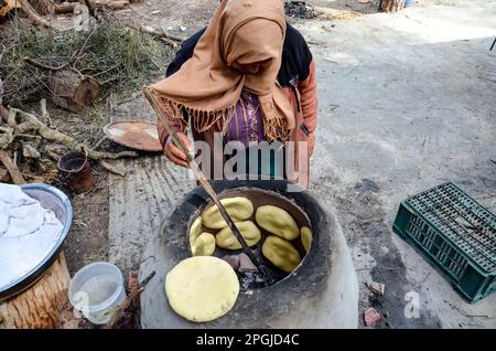 Tunis, Tunesien. 22. März 2023. Tunis, Tunesien, 22. März 2023. Eine tunesische Frau backt das Tabouna-Brot in einem traditionellen Tonofen, bevor sie es auf einem Markt in Tunis verkauft. Tabouna ist ein altes tunesisches Brot aus Weizen-, Grieß- oder Gerstenmehl, das an den Wänden eines traditionellen Terrakotta-Ofens gekocht wird. Tabouna ist besonders beliebt während des heiligen muslimischen Monats Ramadan (Kreditbild: © Hasan mrad/IMAGESLIVE via ZUMA Press Wire). Nicht für den kommerziellen GEBRAUCH! Stockfoto