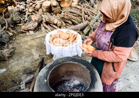 Tunis, Tunesien. 22. März 2023. Tunis, Tunesien, 22. März 2023. Eine tunesische Frau backt das Tabouna-Brot in einem traditionellen Tonofen, bevor sie es auf einem Markt in Tunis verkauft. Tabouna ist ein altes tunesisches Brot aus Weizen-, Grieß- oder Gerstenmehl, das an den Wänden eines traditionellen Terrakotta-Ofens gekocht wird. Tabouna ist besonders beliebt während des heiligen muslimischen Monats Ramadan (Kreditbild: © Hasan mrad/IMAGESLIVE via ZUMA Press Wire). Nicht für den kommerziellen GEBRAUCH! Stockfoto