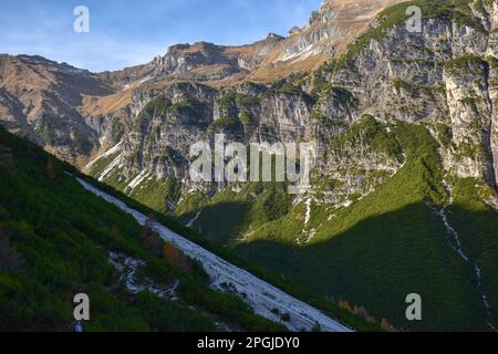 Atemberaubende Luftaufnahme der Dolomitenalpen bei sonnigem Herbsttag mit gelben Lärchen unten und Tal bedeckt von Nebel und hohen Berggipfeln dahinter. Corti Stockfoto