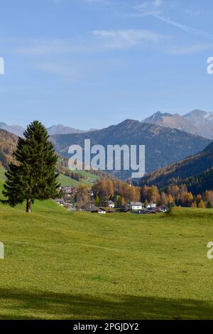 Atemberaubende Luftaufnahme der Dolomitenalpen bei sonnigem Herbsttag mit gelben Lärchen unten und Tal bedeckt von Nebel und hohen Berggipfeln dahinter. Corti Stockfoto