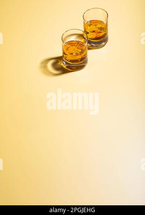 Zwei Whiskey-Gläser mit Eiswürfeln auf goldenem Hintergrund. Draufsicht. Stockfoto