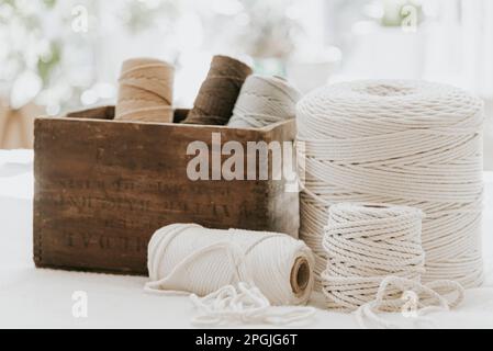 Ein Stapel farbenfroher Fadenspulen in einer Holzkiste auf weißem Hintergrund Stockfoto
