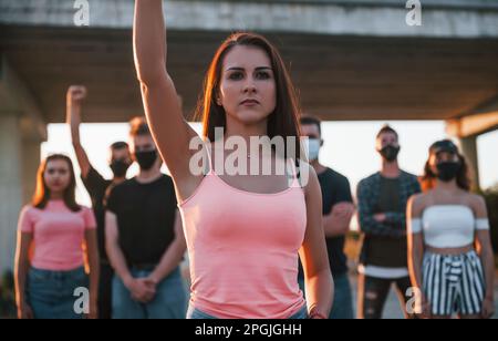 Eine Frau an der Front der Menge. Gruppe von protestierenden jungen Menschen, die zusammenstehen. Aktivisten für Menschenrechte oder gegen die Regierung Stockfoto