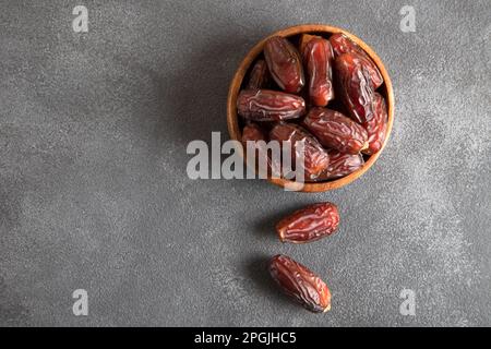 Dattelfrüchte in Holzschüssel auf schwarzem Hintergrund Stockfoto