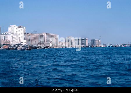 Dubai UAE 1976 – Blick auf die Skyline von Deira vom Creek aus, mit Dhows am Kai in Dubai in den Vereinigten Arabischen Emiraten Stockfoto