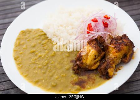 Hähnchenflügel mit pürierten Erbsen, Reis und eingelegten Zwiebeln auf weißem Teller Stockfoto