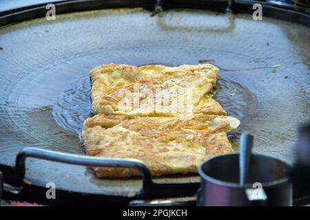 Roti in einer tiefen Bratpfanne, mit Granulatzucker bestreut und mit gesüßter Kondensmilch Stockfoto