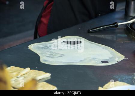 Roti in einer tiefen Bratpfanne, mit Granulatzucker bestreut und mit gesüßter Kondensmilch Stockfoto