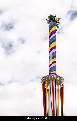 Farbenfrohe Bänder hängen an einer traditionellen englischen Maypole auf einer Dorffeier. Stockfoto