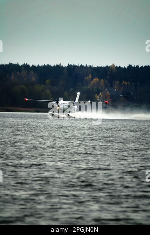 Das zweimotorige Wasserflugzeug ein Wasserflugzeug steigt aus dem Wasser, aus dem Waldsee, dem nördlichen Land auf. Wasserflugzeug Stockfoto