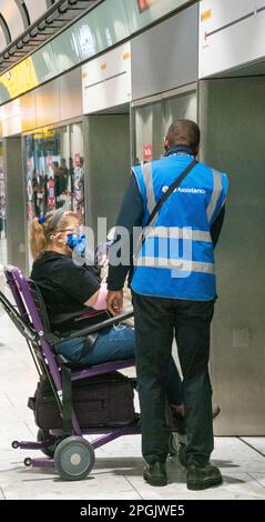 Assistentin, die Frau im Rollstuhlzug zum Terminal 5, Flughafen Heathrow, London, UK, hilft Stockfoto