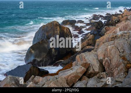 Wellen schlagen gegen felsige Küsten, türkisfarbenes Wasser an windigen sonnigen Tagen, Lofoten-Inseln in der Nähe des Strandes Haukland, Norwegen. Stockfoto
