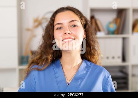 Positive Ärztin in blauem Hemd im medizinischen Zentrum stehend Stockfoto