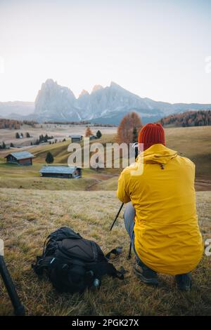 Eine vertikale Rückansicht eines professionellen Fotografen, der Fotos von einem Berg auf einem Stativ macht Stockfoto