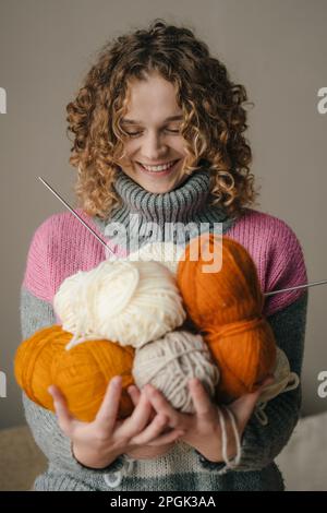Junge, lockige Frau mit vielen bunten Garn-clews. Konzept des freiberuflichen kreativen Arbeitens und Lebens. Häuslicher Lebensstil. Modeporträt Stockfoto