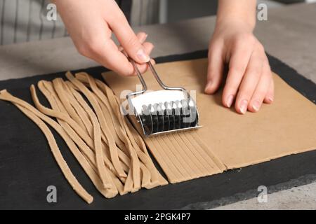 Frau schneidet Teig für Soba am Tisch, Nahaufnahme Stockfoto