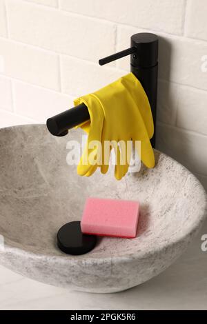 Gummihandschuhe am Wasserhahn im Waschbecken Stockfoto