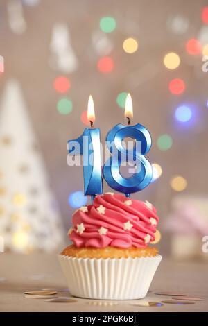 Zum 18. Geburtstag. Köstlicher Cupcake mit zahlenförmigen Kerzen für eine Party auf dem Tisch Stockfoto