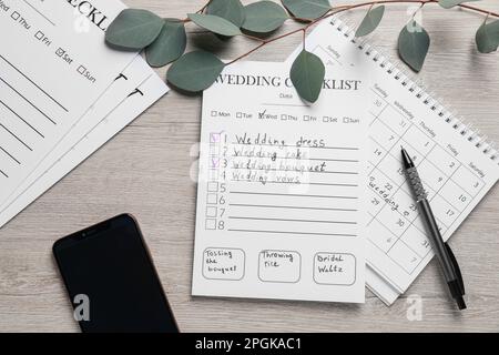 Flache Liegezusammenstellung mit Hochzeits-Checkliste und Kalender auf Holztisch Stockfoto