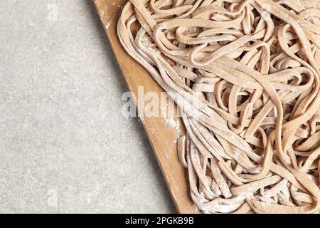 Ungekochter, hausgemachter Soba mit Holzbrett auf einem hellen Tisch, Blick von oben. Platz für Text Stockfoto