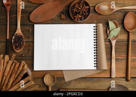 Leeres Rezeptbuch, Gewürze und Küchenutensilien auf Holztisch, flach liegend. Platz für Text Stockfoto