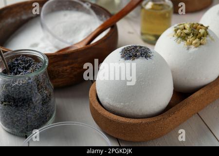 Verschiedene Badebomben und Zutaten auf weißem Holztisch, Nahaufnahme Stockfoto