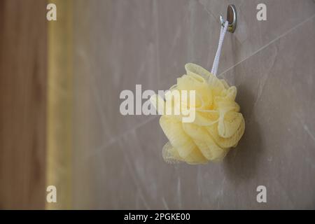 Gelber Schwamm, der an grauen Wänden im Badezimmer hängt Stockfoto