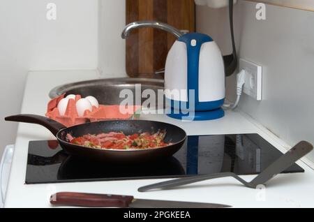 Ich koche Rührei mit Schinken. Zwiebeln und Gemüse in einem Topf braten Stockfoto