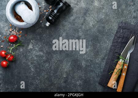 Hintergrund der Kochkunst. Grüne Rosmarin-Äste, Olivenöl, Knoblauch, Pfefferkörner und heiße Paprika auf dunklem Betontisch. Lebensmittelzutaten Top vi Stockfoto