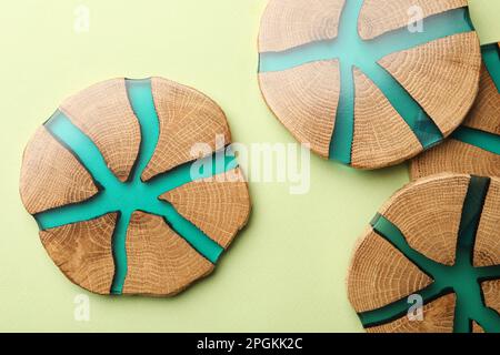 Stilvolle Untersetzer mit Holzbechern auf hellgrünem Hintergrund, flach liegend Stockfoto