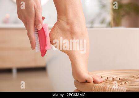 Frau, die Bimsstein benutzt, um tote Haut aus den Füßen im Badezimmer zu entfernen, Nahaufnahme Stockfoto