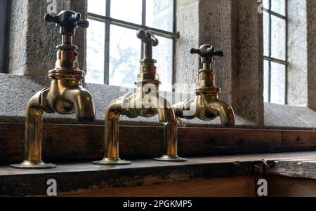 Messing-Wasserhähne in Castle Dropo, Drewsteignton, Devon, England, Großbritannien Stockfoto