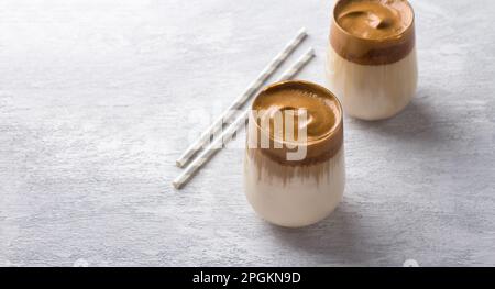 Zwei Gläser mit Dalgona-Kaffee, kalter Cocktail mit Schlagsahne mit Schokoladenspäne, beliebtes trendiges Getränk auf einer leichten Struktur Stockfoto