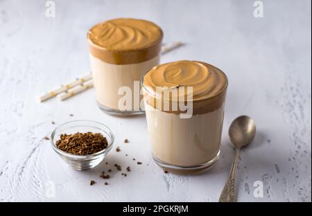 Zwei Gläser mit Dalgona-Kaffee, kalter Cocktail mit Schlagsahne, beliebtes trendiges Getränk auf einem leicht strukturierten Hintergrund Stockfoto