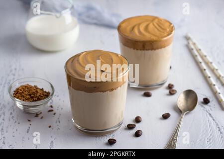Zwei Gläser mit Dalgona-Kaffee, kalter Cocktail mit Schlagsahne, beliebtes trendiges Getränk auf einem leicht strukturierten Hintergrund Stockfoto