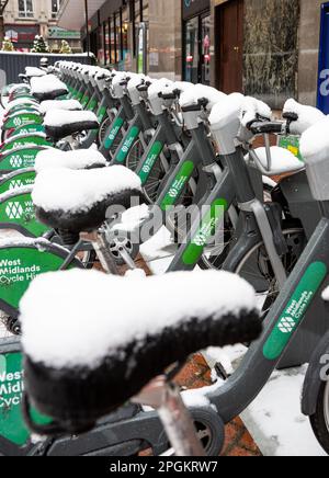 Eine Reihe ungenutzter West Midlands Cycle Verleih Fahrräder, die von starkem Schneefall bedeckt und im Winter nicht genutzt wurden Stockfoto