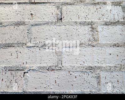 Extreme Nahaufnahme einer grau bemalten Ziegelwand mit grobem Mörtel Stockfoto