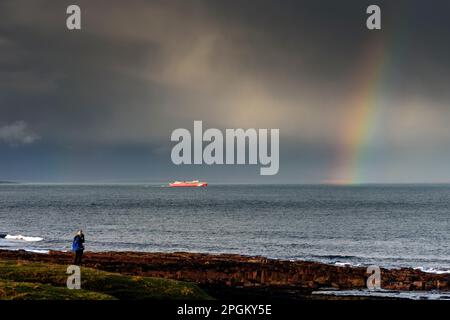 Die Fähre Gills Bay nach Orkney, der MV Alfred, unter stürmischem Himmel und Regenbogen, auf dem Pentland Firth, nahe John O'Groats, Caithness, Schottland, Großbritannien. Stockfoto