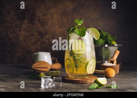 Iced Mojito Cocktail Long Rum Drink mit frischer Minze, frischem Thymian, Limettensaft, Rohrzucker und Limonade auf dunklem abstraktem Hintergrund. Sommereisgetränk und Stockfoto