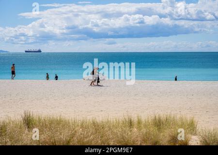 Tauranga Neuseeland - März 22 2023: Mo. Maunganui Hauptstrand im Hintergrund mit Menschen, die Surfbrett tragen. Stockfoto