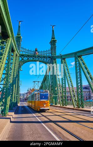 Die hellgelbe Retro-Straßenbahn auf der Liberty Bridge, Budapest, Ungarn Stockfoto